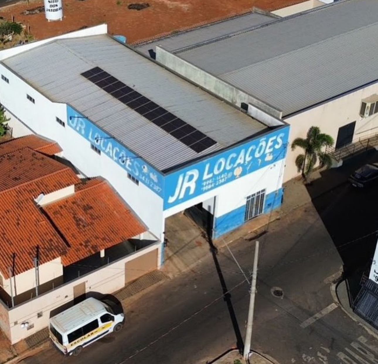 Vista aérea da sede da JR Locações em Prata MG, com fachada azul e galpão de equipamentos